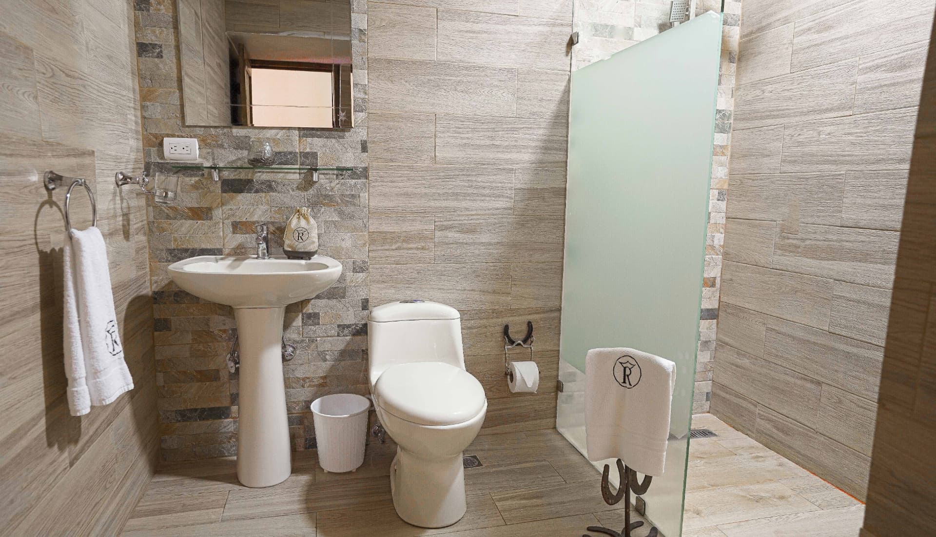 Baño privado con ducha en cristal y acabados en piedra