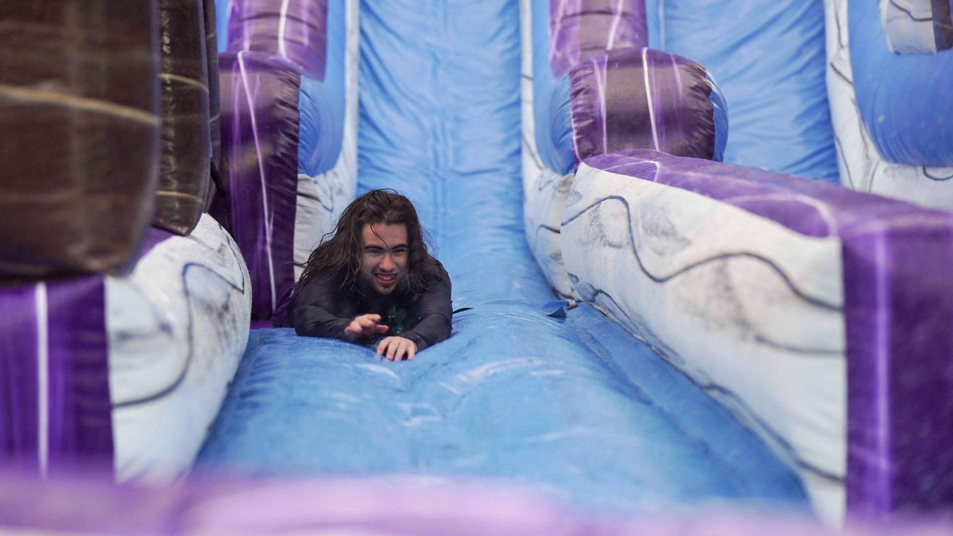 Joven deslizándose por el tobogán inflable de agua